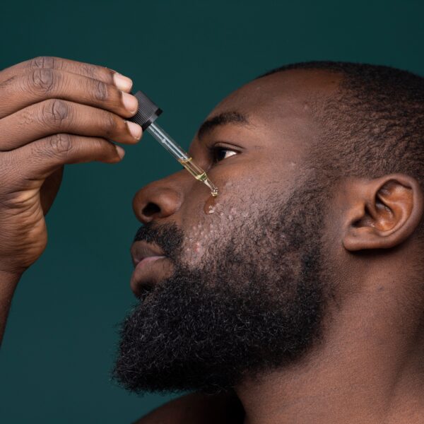 african,bearded,man,with,pimples,and,skin,problems,applying,oil